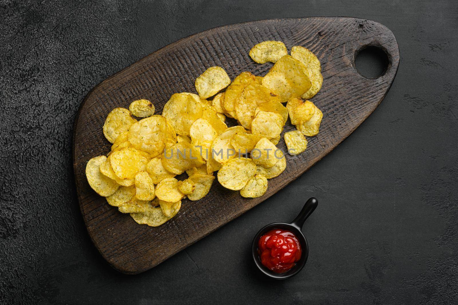 Dill Pickle Flavored Potato Chips on black dark stone table background, top view flat lay, with copy space for text by Ilianesolenyi