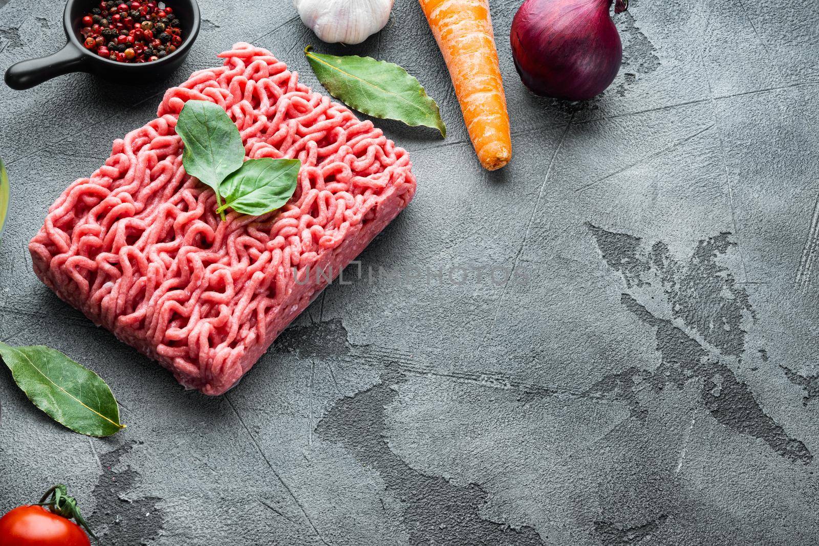 Ingredients for cooking Bolognese sauce, minced beef meat tomatoe and herbs set, on gray stone background, with copy space for text