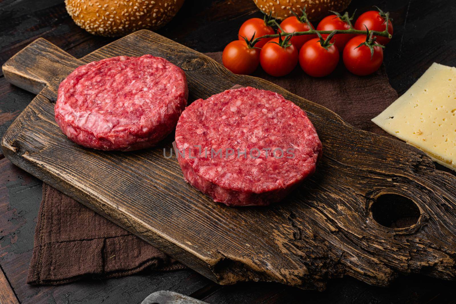 Raw fresh large beef burger, on old dark wooden table background