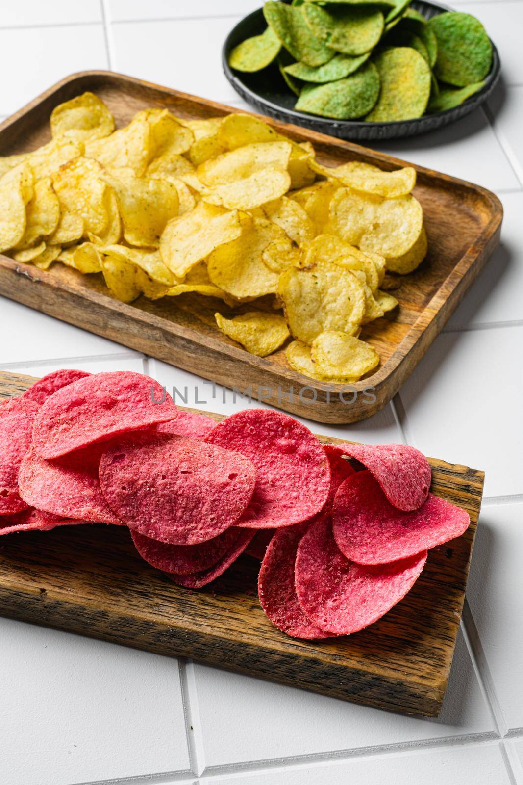 Potato chips pink colored, on white ceramic squared tile table background