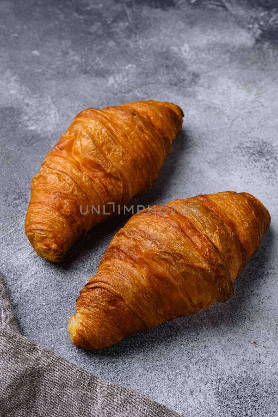 Fresh croissants on table set, on gray stone table background by Ilianesolenyi