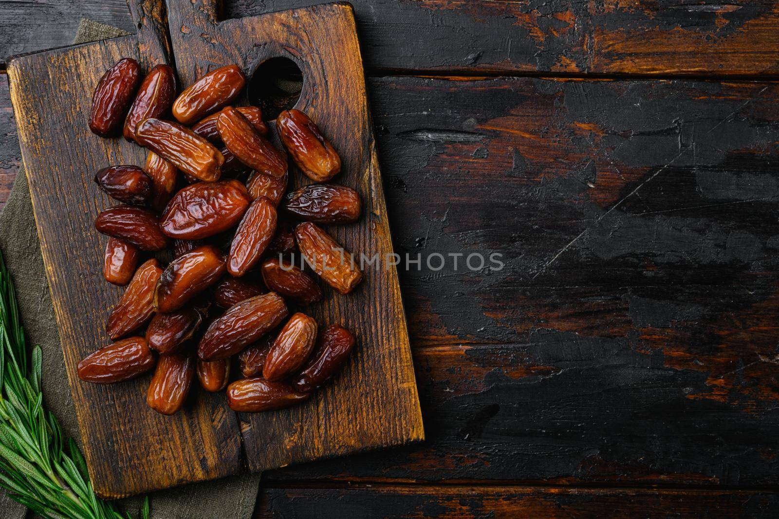 Dried date palm fruits set, on old dark wooden table background, top view flat lay, with copy space for text by Ilianesolenyi