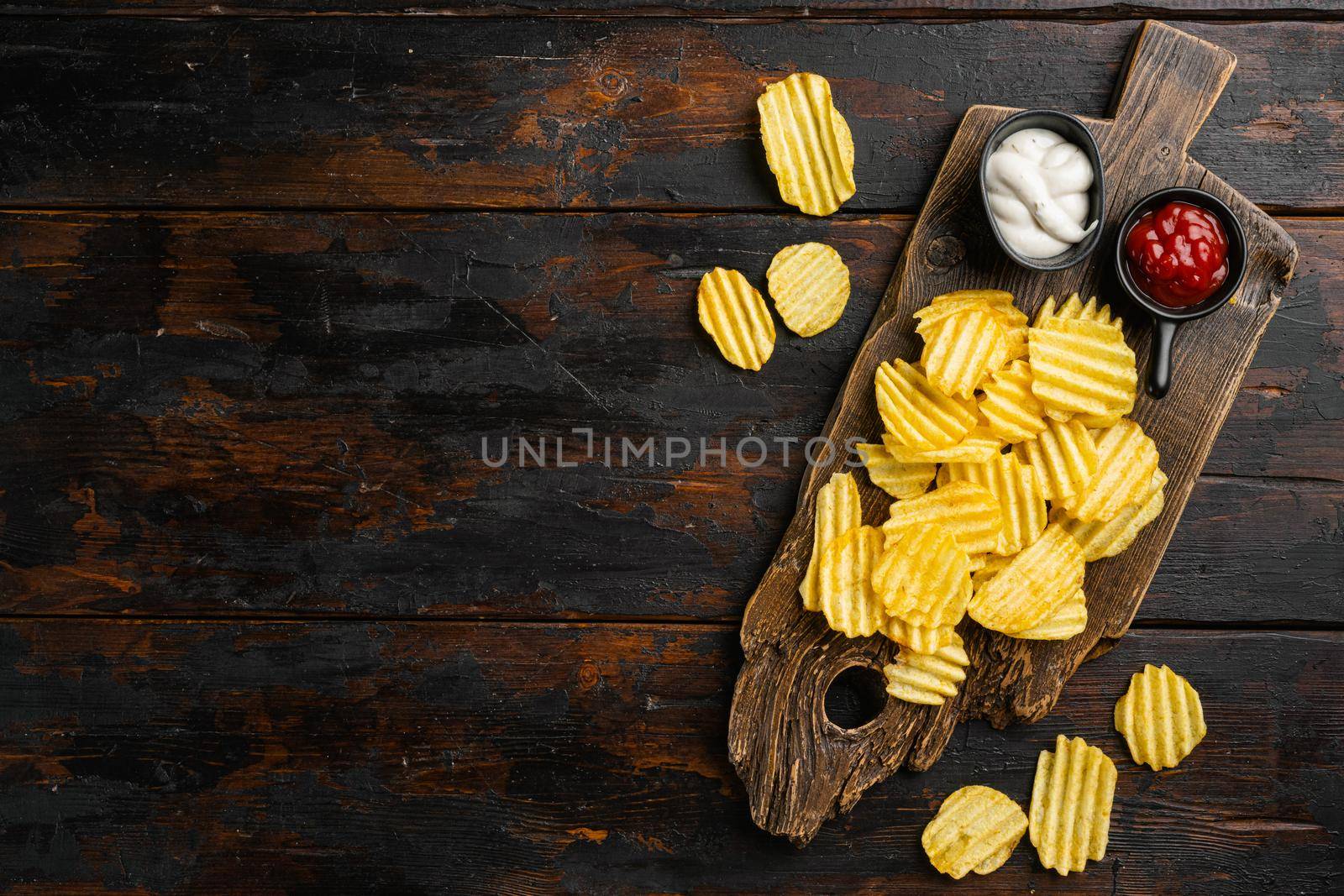 Wavy Reduced Fat chip on old dark wooden table background, top view flat lay, with copy space for text by Ilianesolenyi