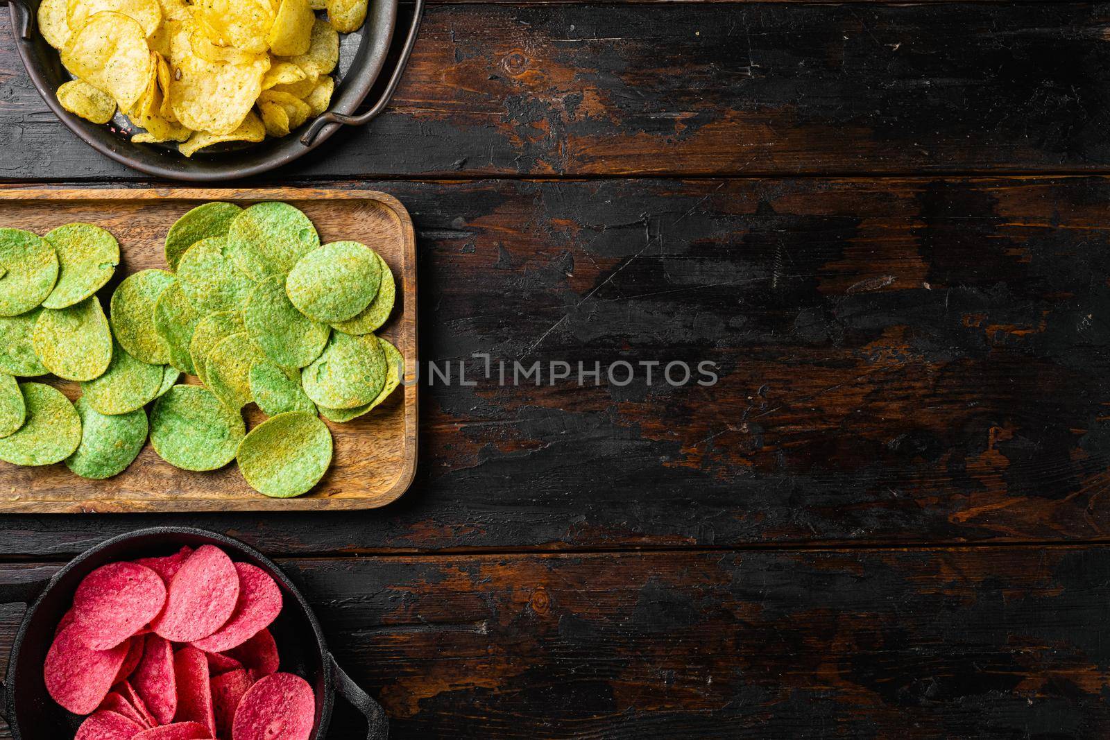 Crispy potato chips, on old dark wooden table background, top view flat lay, with copy space for text