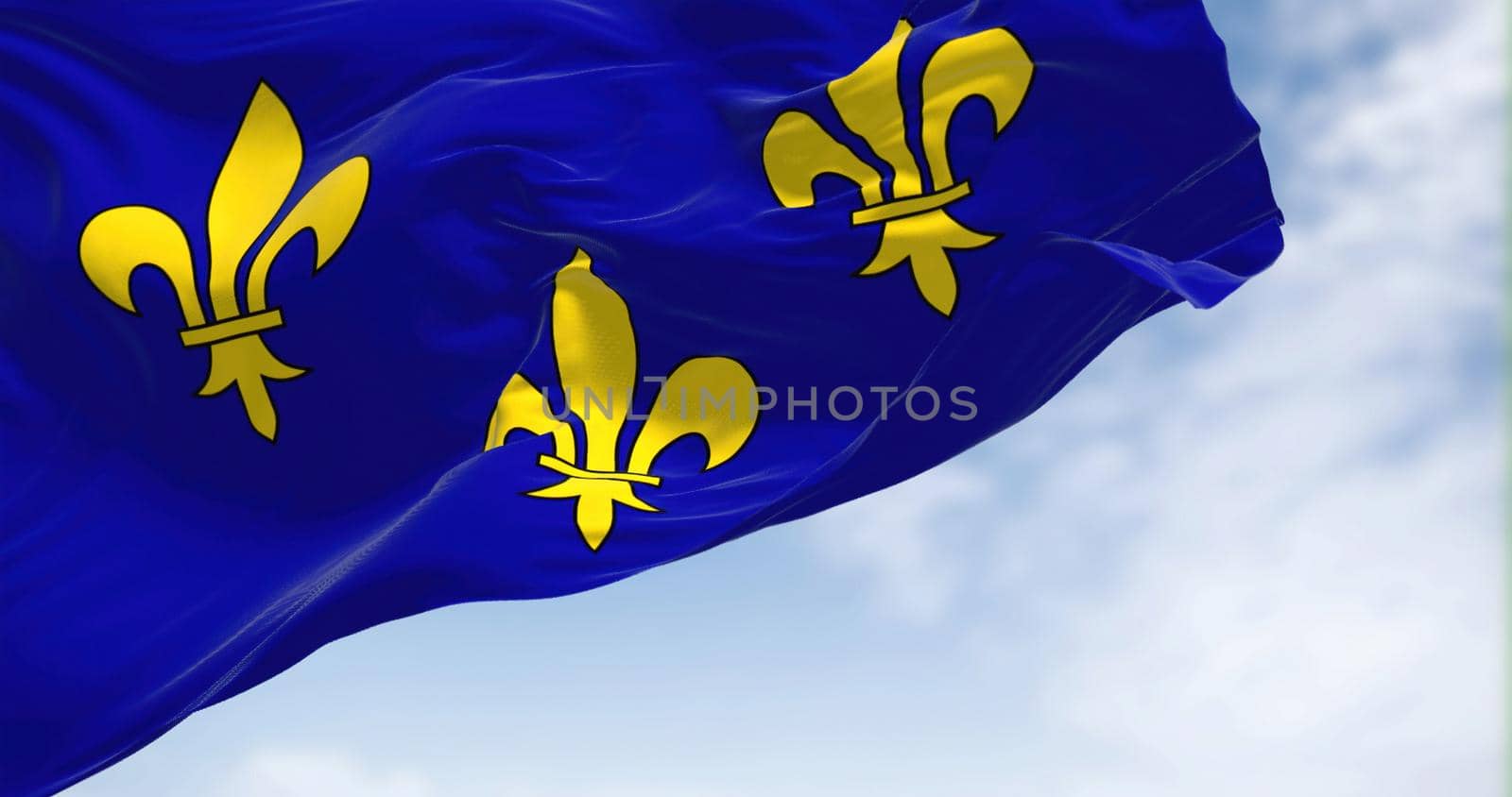 The flag of Ile de France region waving in the wind on a clear day. Ile de France is the most populous of the eighteen regions of France