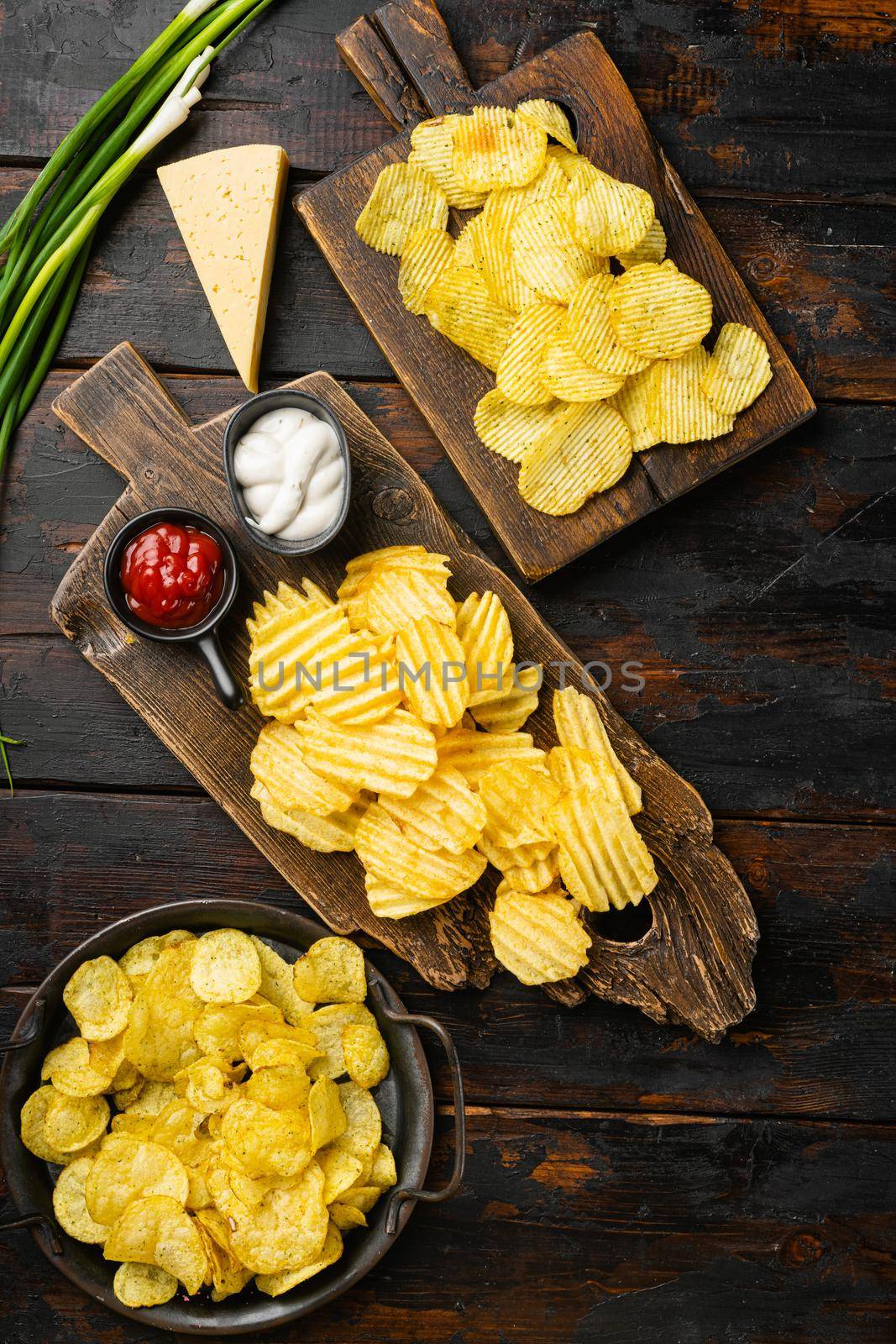 Sour Cream Onion Flavored Potato Chips on old dark wooden table background, top view flat lay by Ilianesolenyi