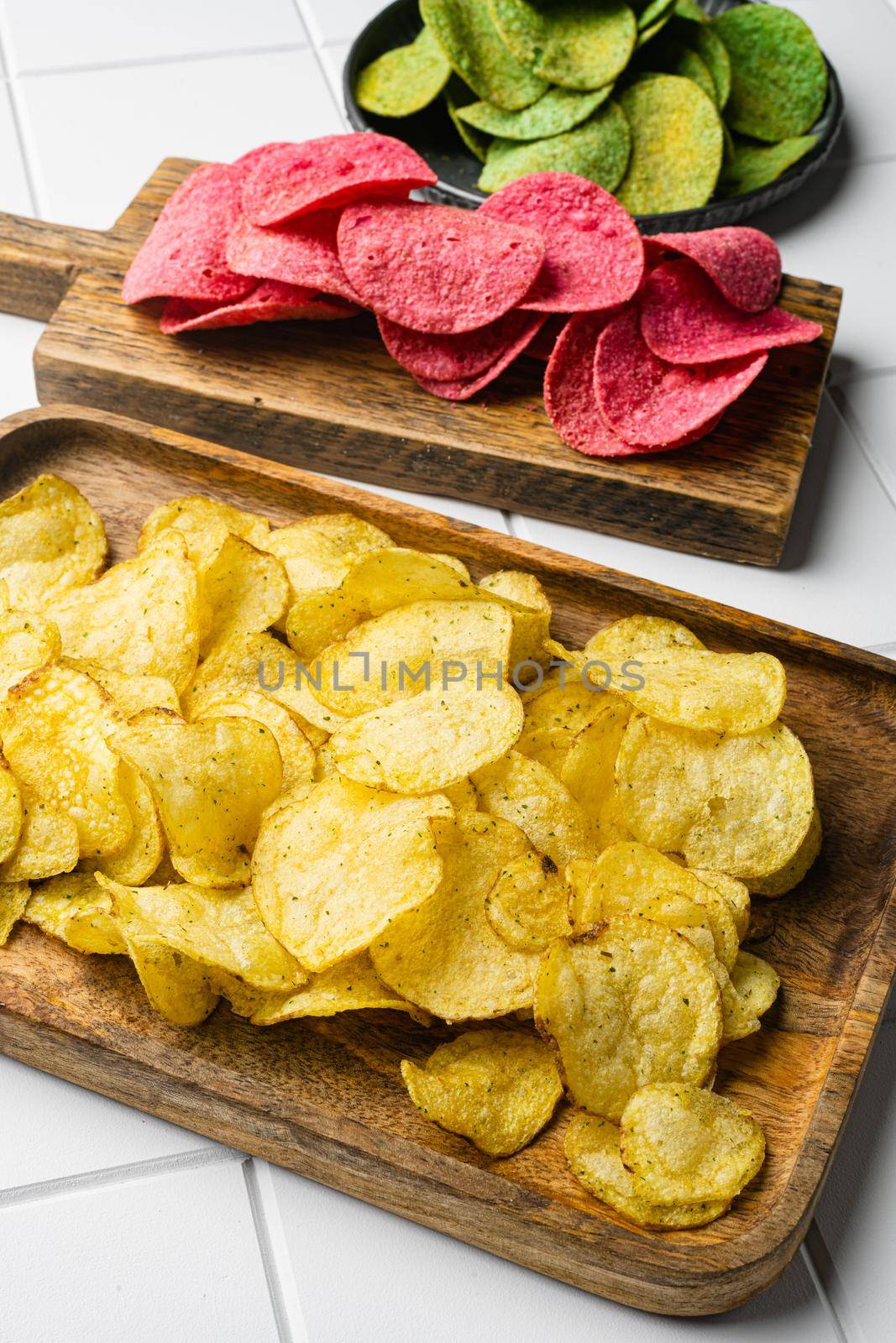 Cheddar Sour Cream Flavored Potato Chips on white ceramic squared tile table background by Ilianesolenyi