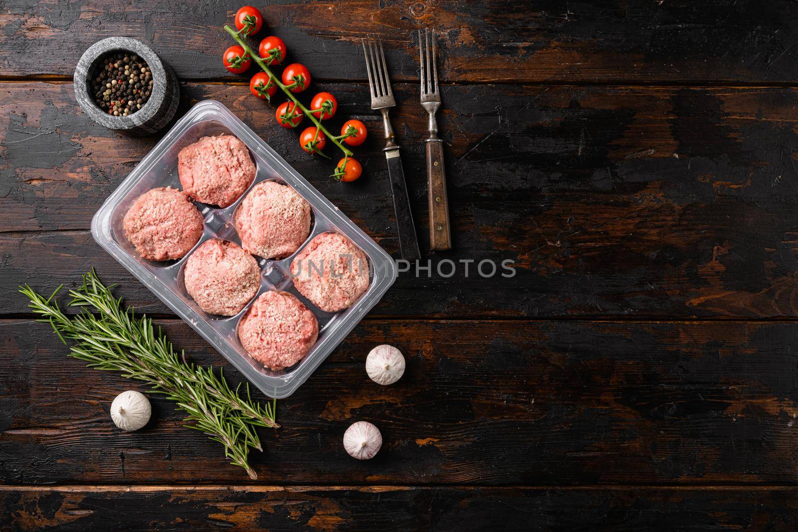 Raw fresh chicken cutlets in plastic transparent container set, on old dark wooden table background, top view flat lay, with copy space for text