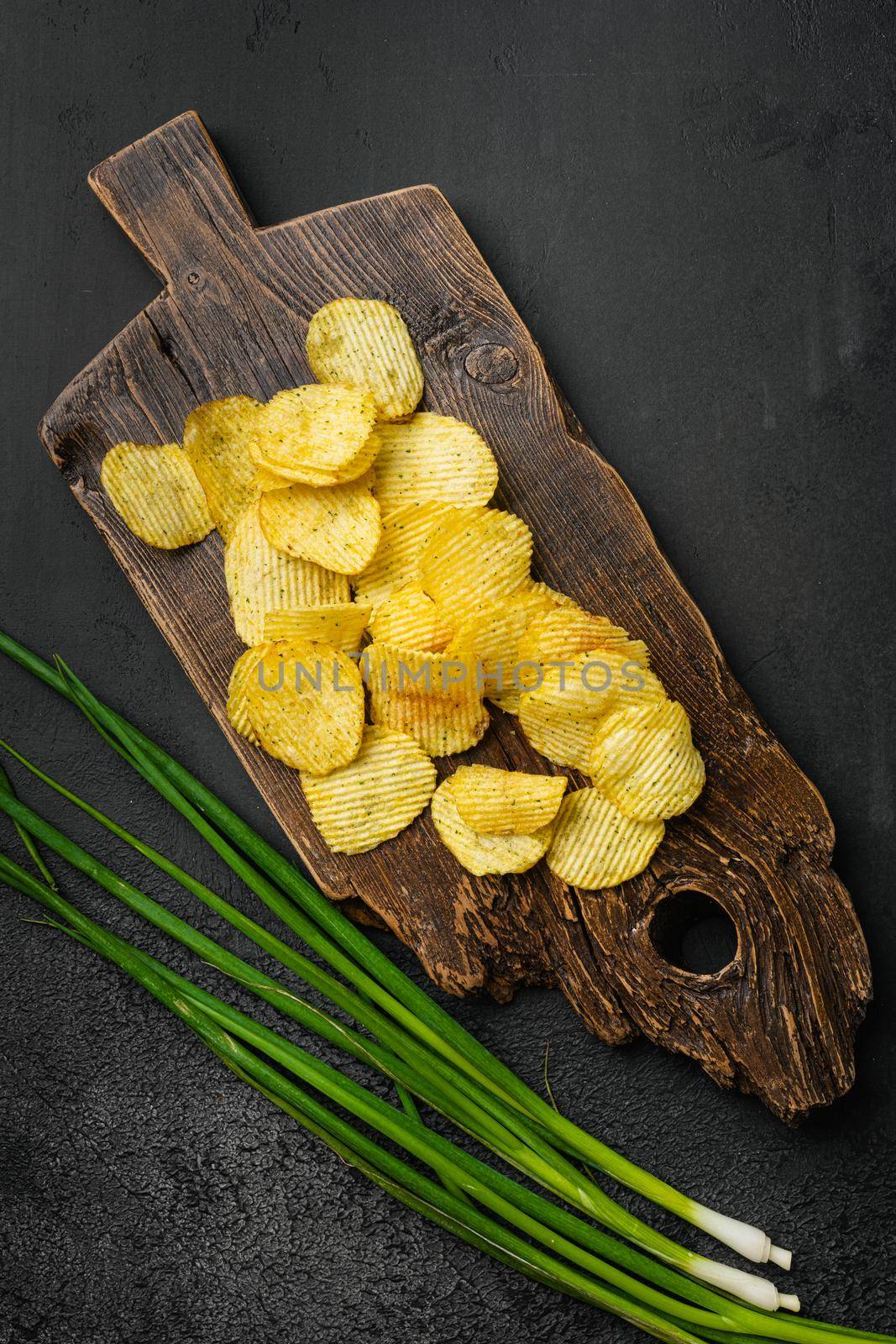 Wavy Reduced Fat chip, on black dark stone table background, top view flat lay
