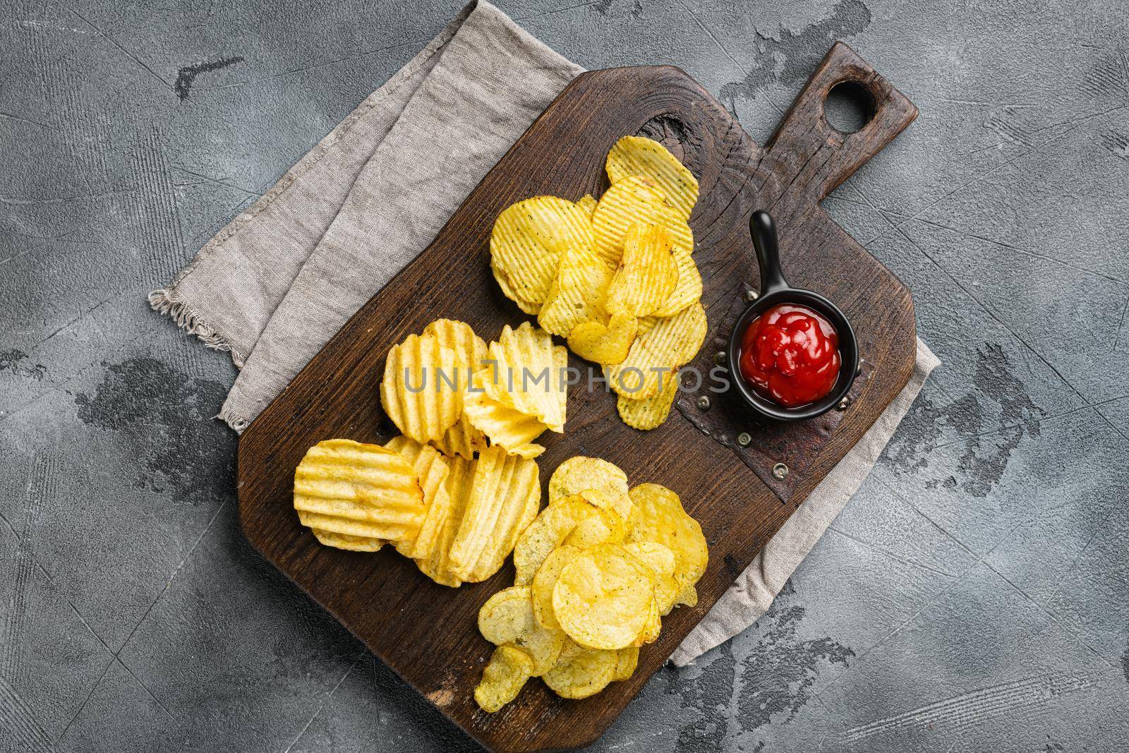 Crispy potato chips, on gray stone table background, top view flat lay, with copy space for text