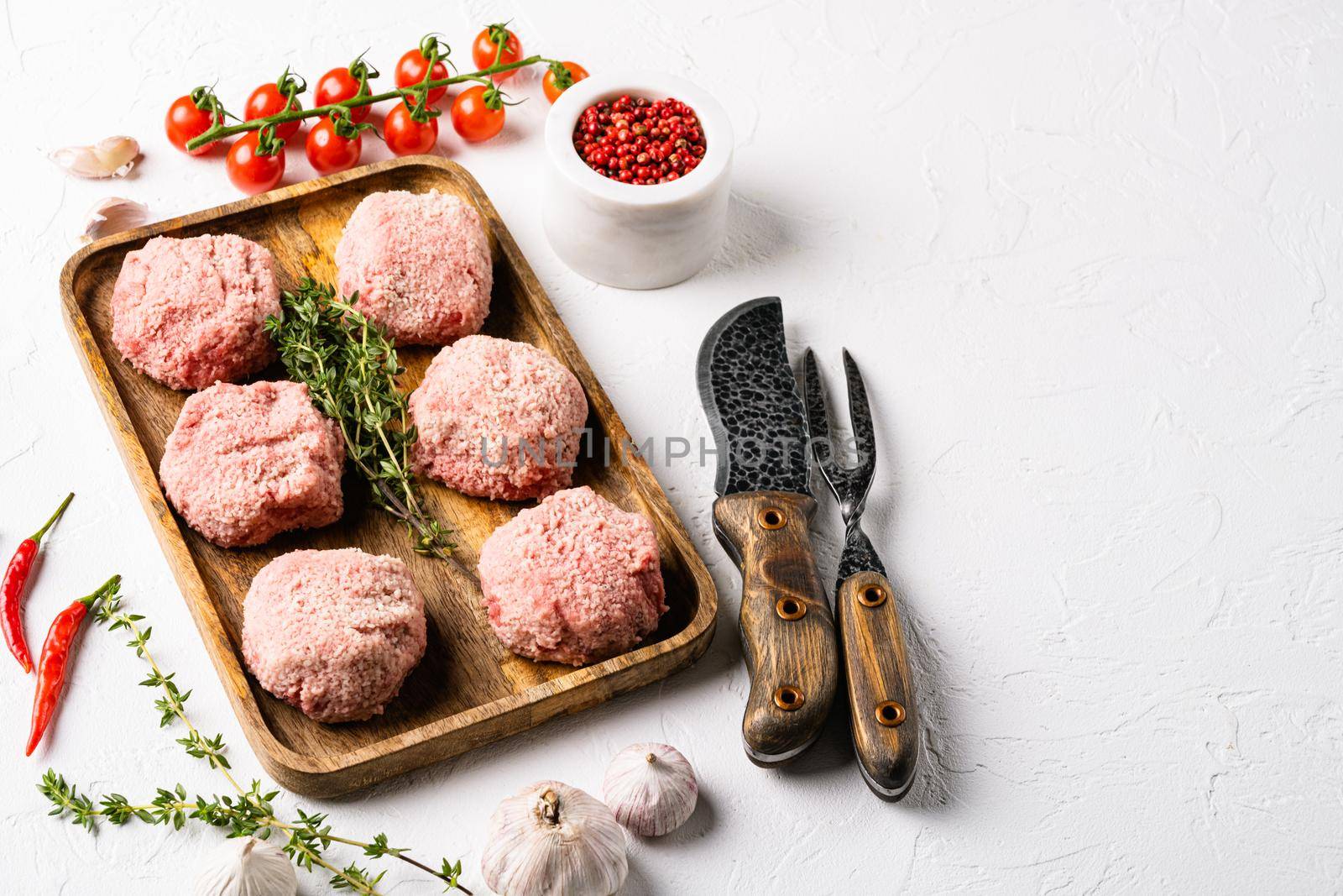 Raw burgers cutlets from organic meat, on white stone table background, with copy space for text by Ilianesolenyi