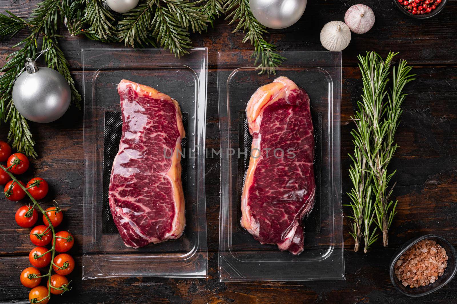 Vacuum packed organic raw beef set, on old dark wooden table background, top view flat lay