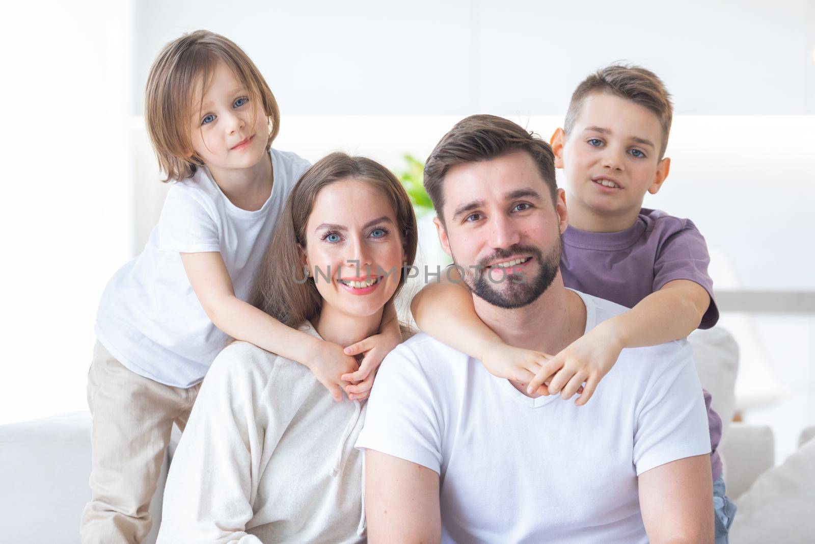 Happy family of parents with children sitting together on sofa at home