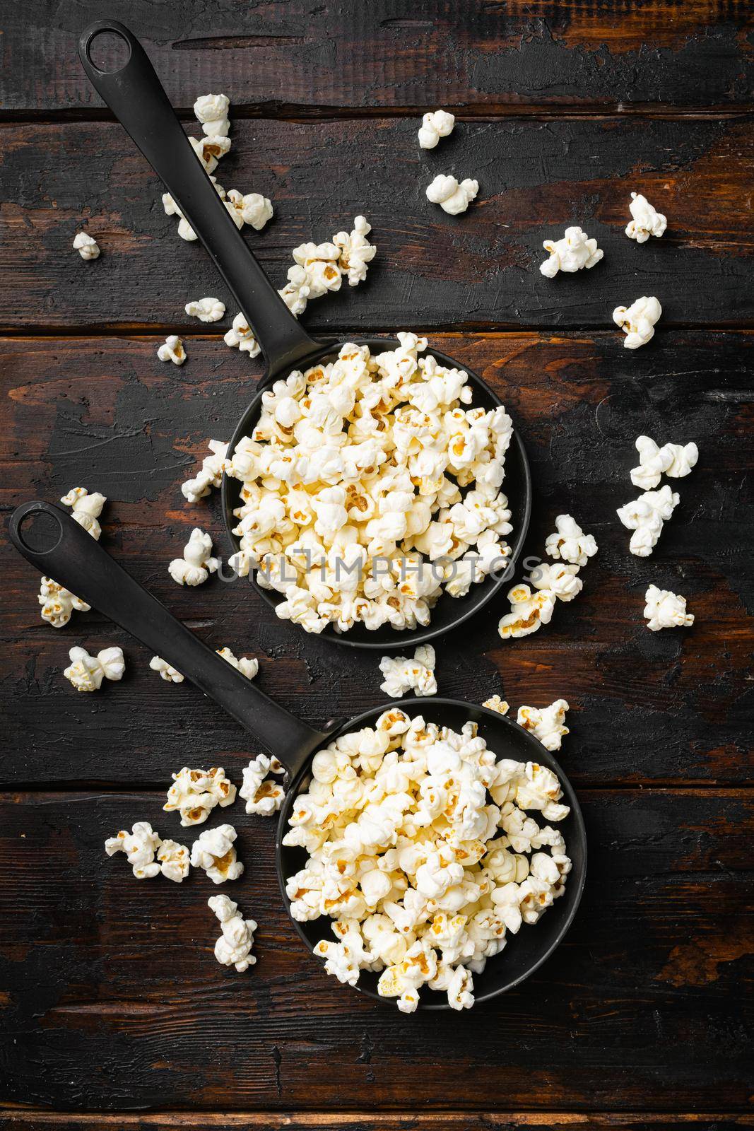 Heap of salted popcorn on old dark wooden table background, top view flat lay by Ilianesolenyi