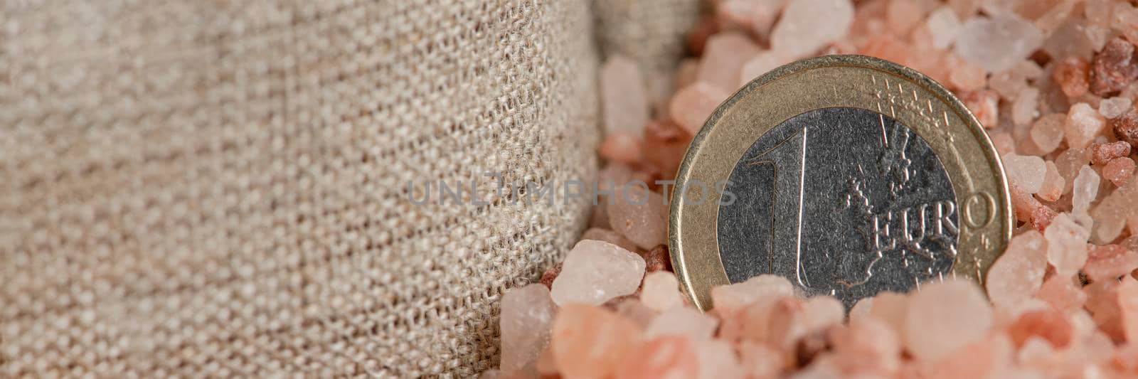 Salt price. Large crystals of pink Himalayan salt, close-up. A coin in a pile of salt as a symbol of rising prices. by SERSOL