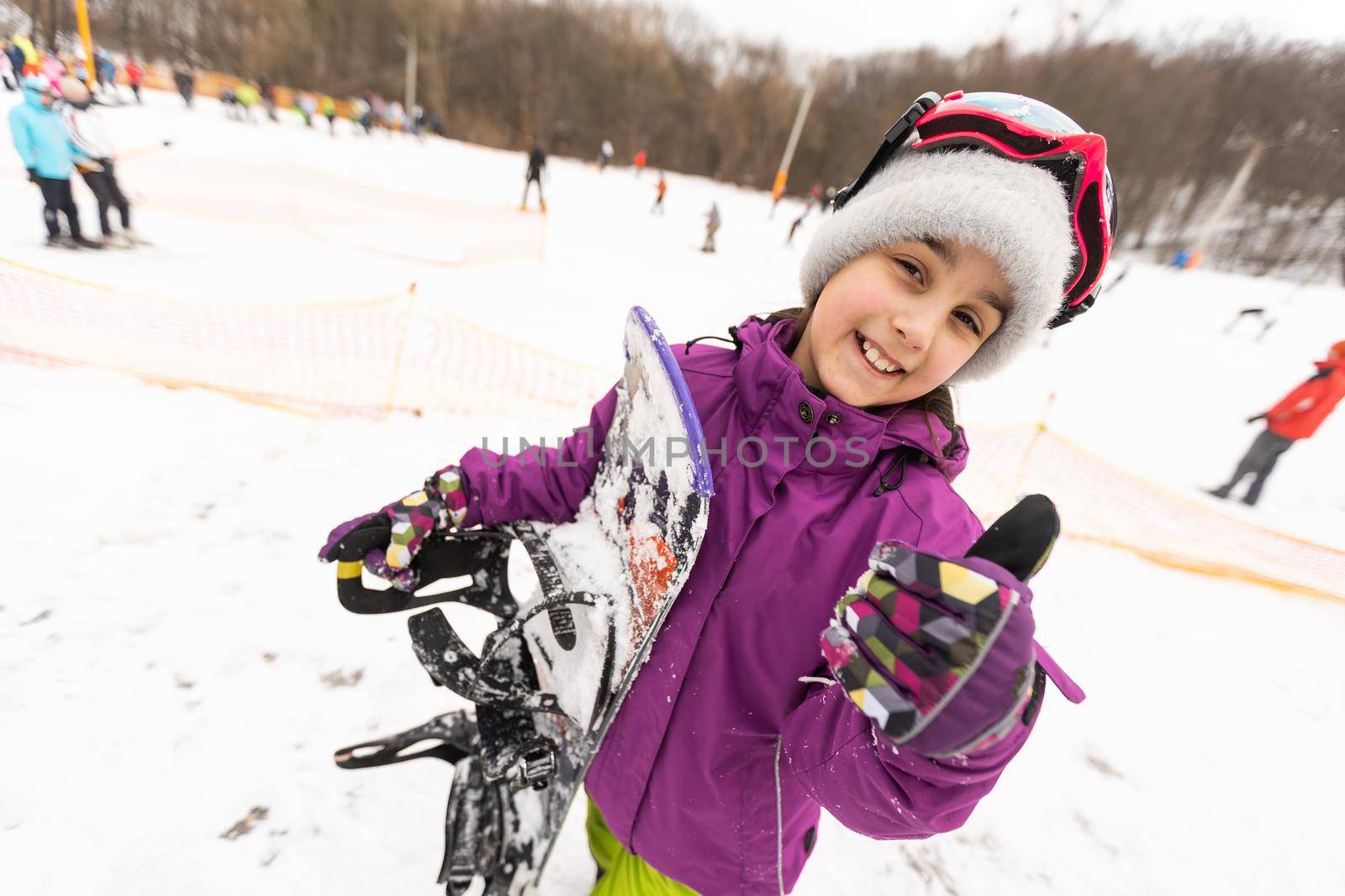 little cute girl learning to ride a children's snowboard, winter sports for the child, safety of active sports