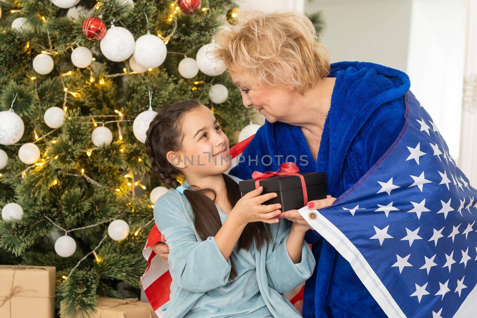 Family holding flag of USA at christmas. grandmother and granddaughter.