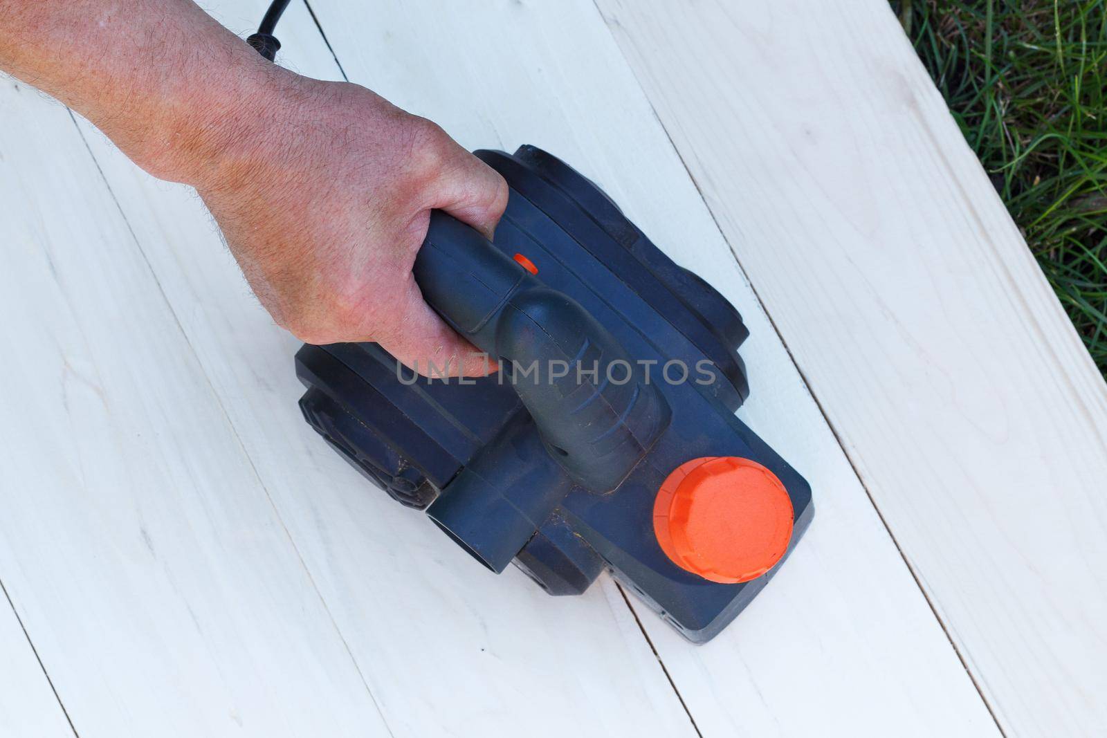 Man sanding wood with orbital sander in workshop