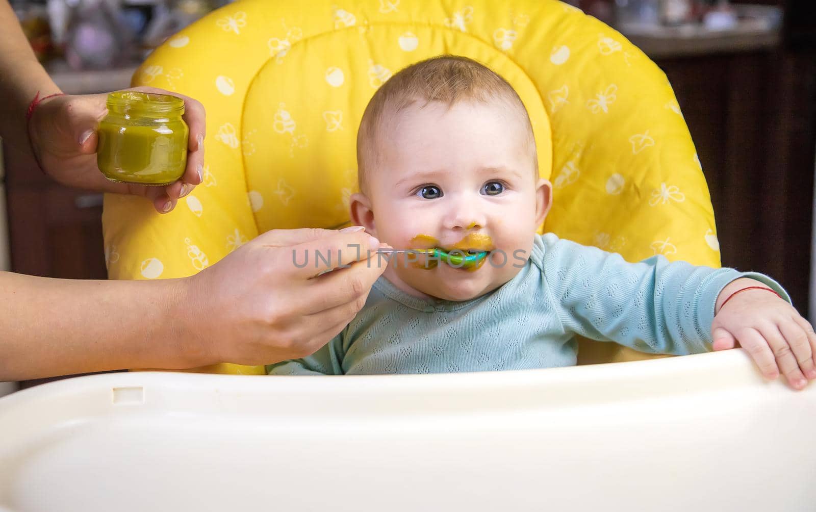 Little baby is eating broccoli vegetable puree. Selective focus. people.