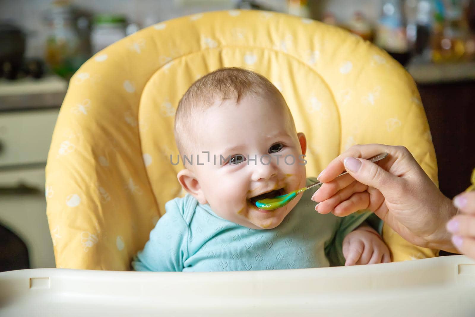 Little baby is eating broccoli vegetable puree. Selective focus. people.