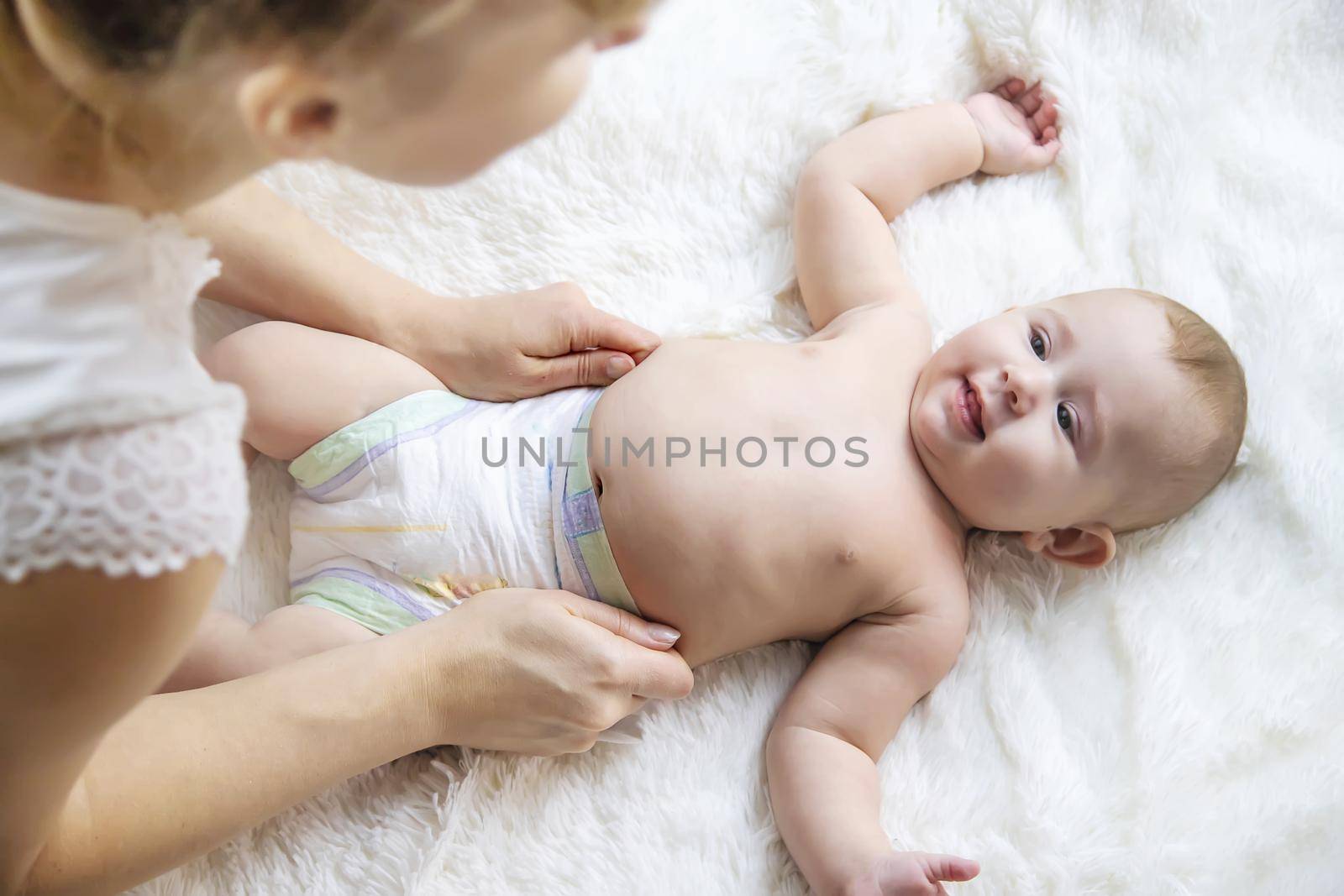 The mother is changing the baby's diaper. Selective focus. People.