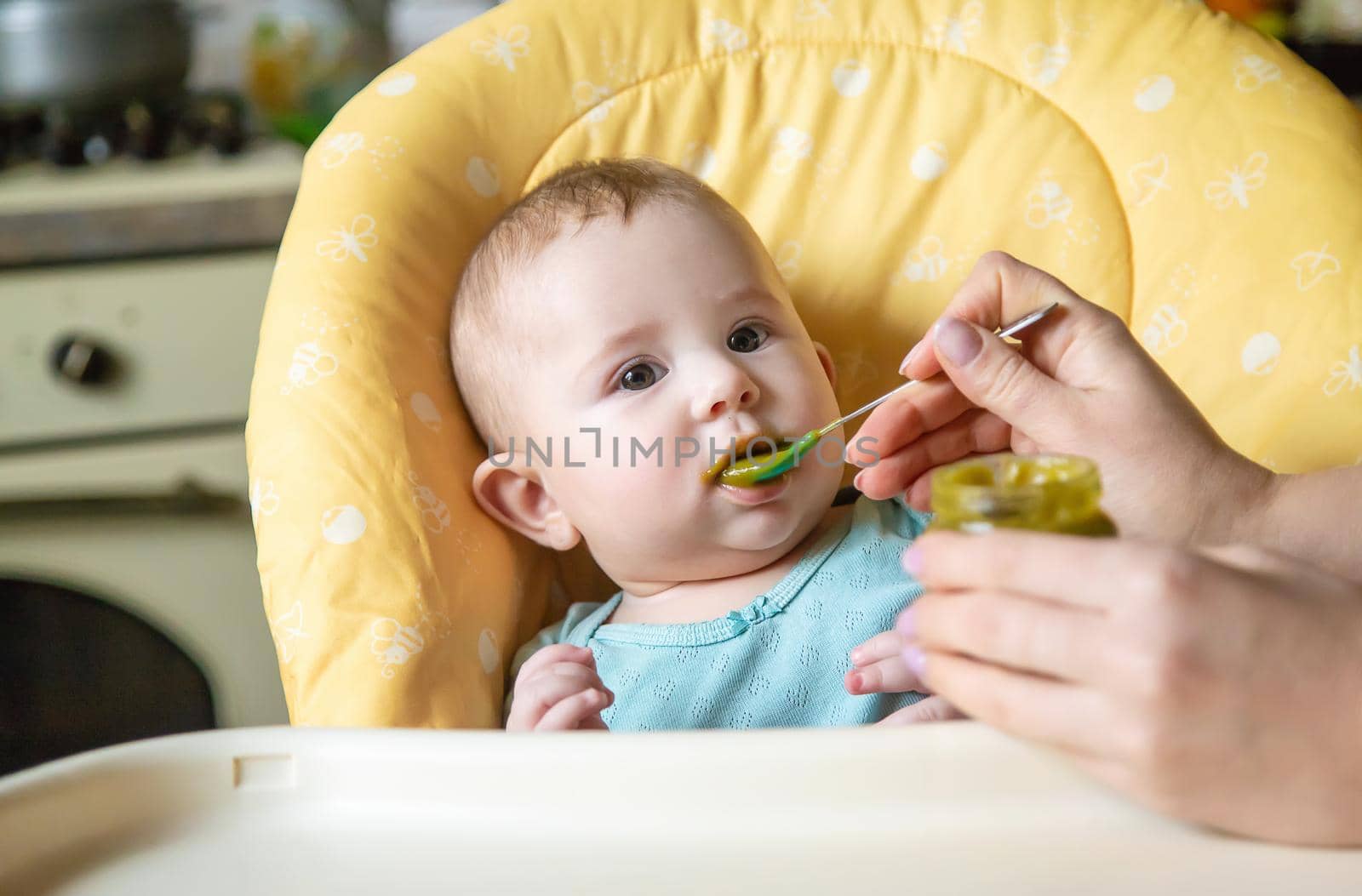 Little baby is eating broccoli vegetable puree. Selective focus. by yanadjana