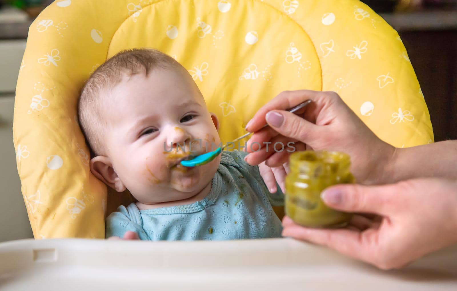 Little baby is eating broccoli vegetable puree. Selective focus. by yanadjana