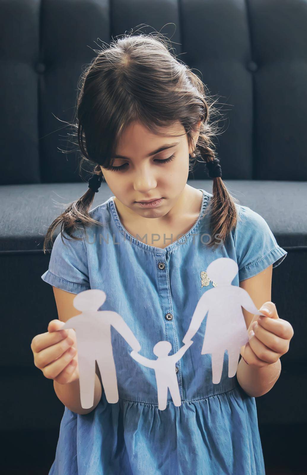 Child with a paper family in his hands. the concept of divorce, custody and child abuse. Selective focus. by yanadjana