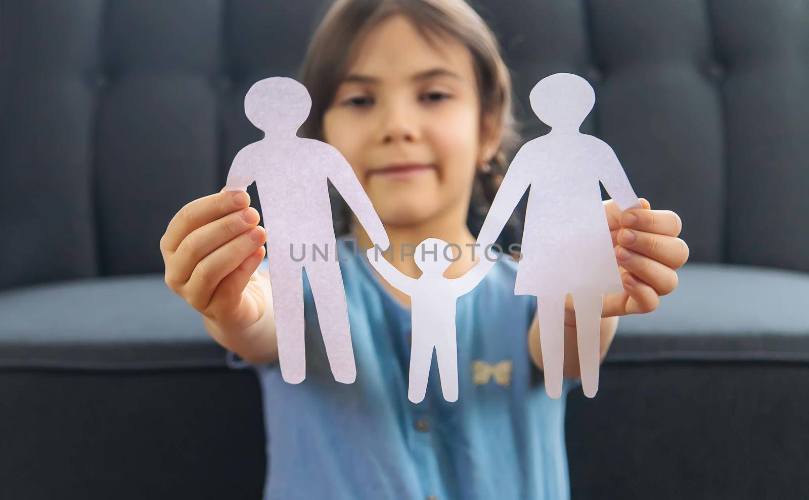 Child with a paper family in his hands. Selective focus. by yanadjana