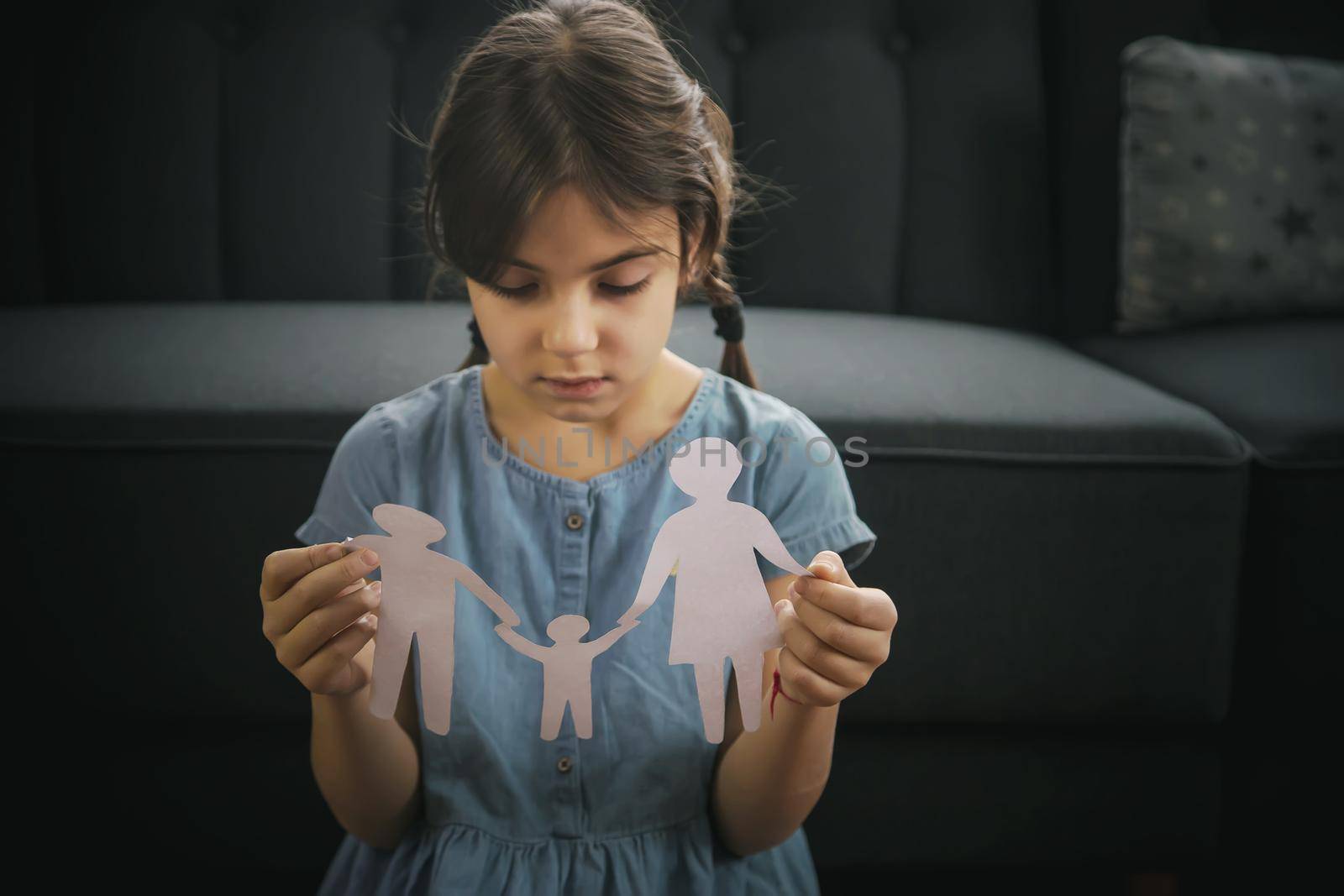 Child with a paper family in his hands. the concept of divorce, custody and child abuse. Selective focus. by yanadjana