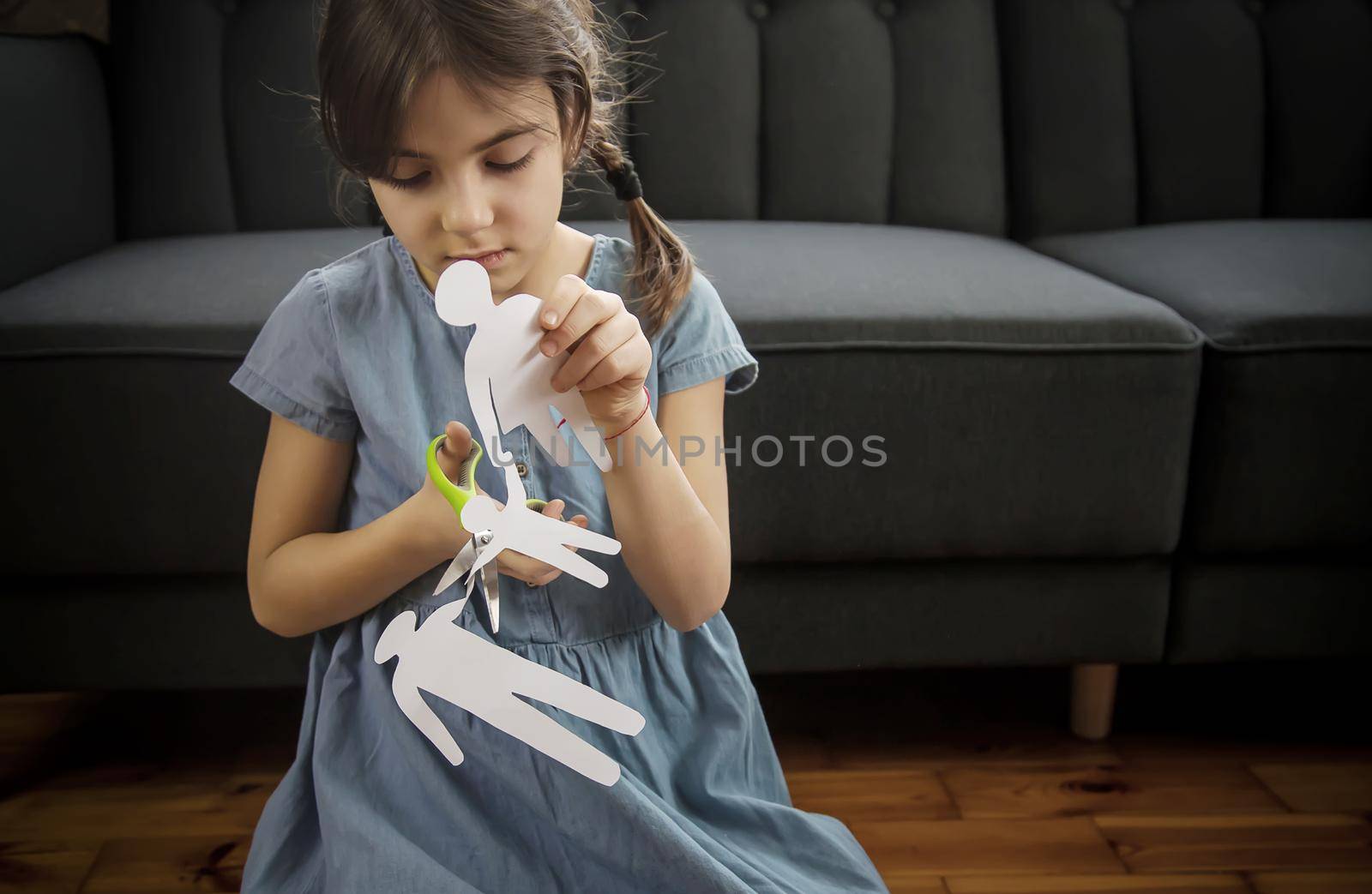 Child with a paper family in his hands. the concept of divorce, custody and child abuse. Selective focus. People.