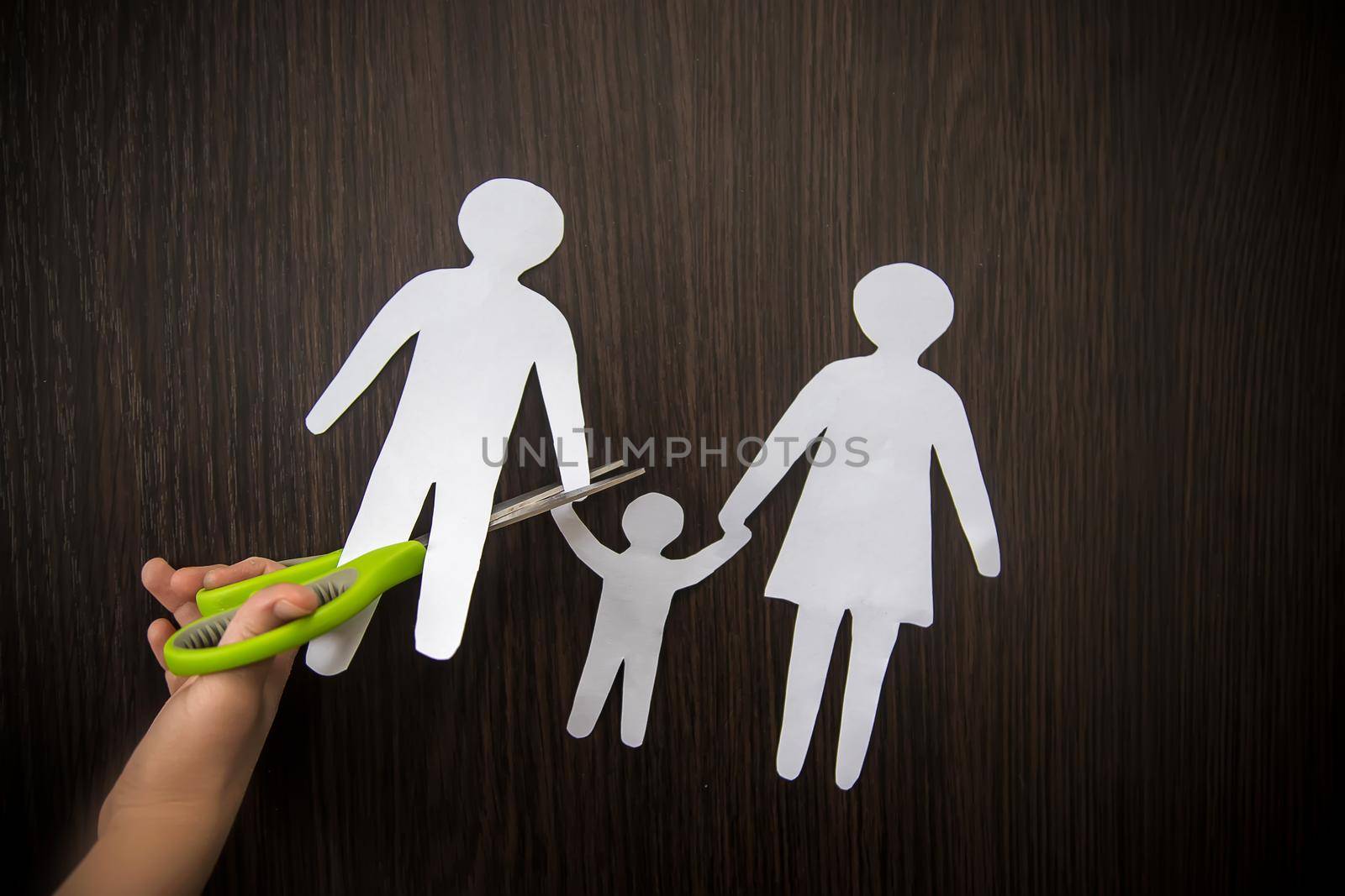 Child with a paper family in his hands. the concept of divorce, custody and child abuse. Selective focus. by yanadjana