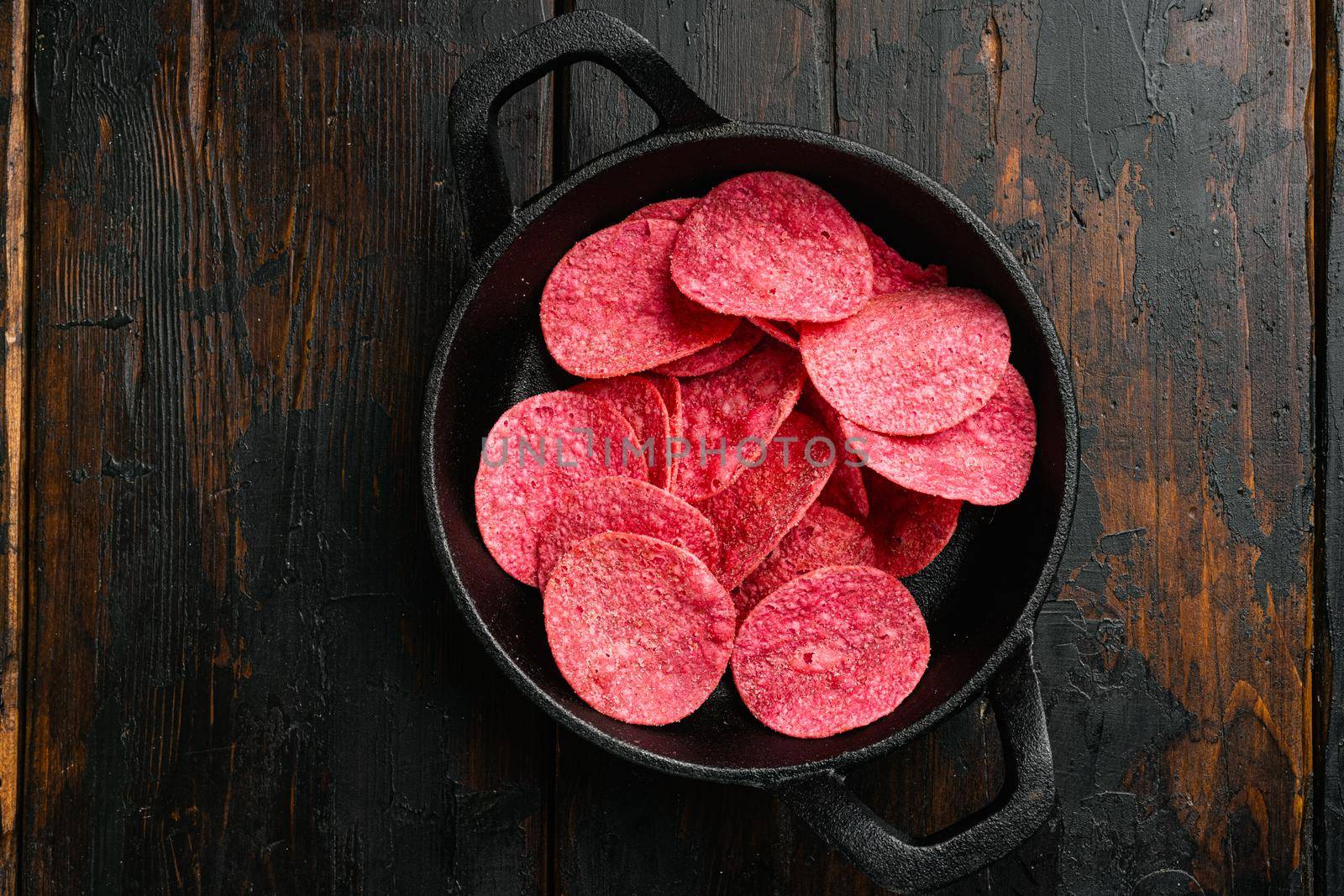 Hickory BBQ Flavored red Potato Chips on old dark wooden table background, top view flat lay, with copy space for text by Ilianesolenyi