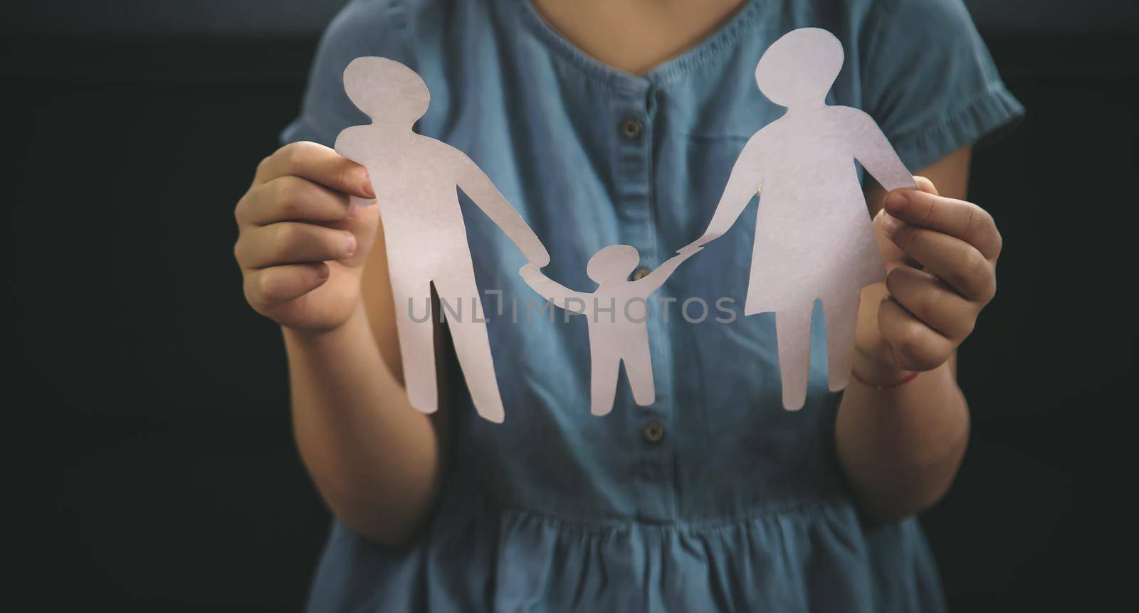 Child with a paper family in his hands. the concept of divorce, custody and child abuse. Selective focus. People.