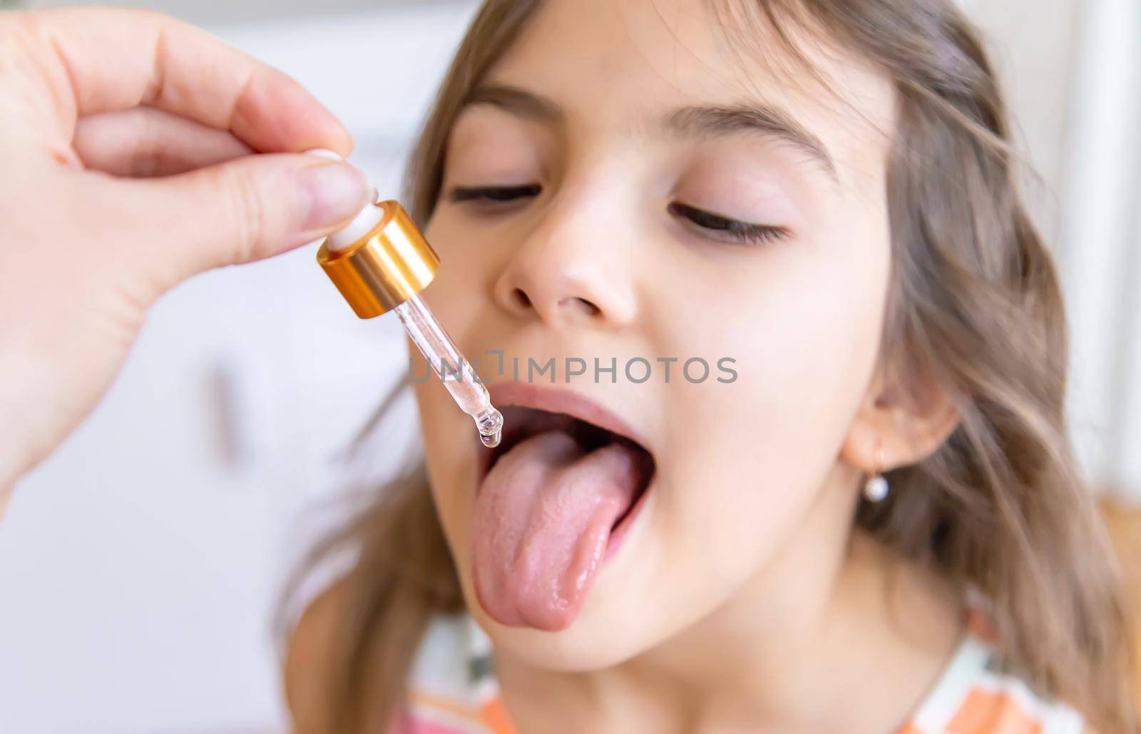 mother giving vitamin drops with dropper to her child. dietary supplements for kids. Selective focus.