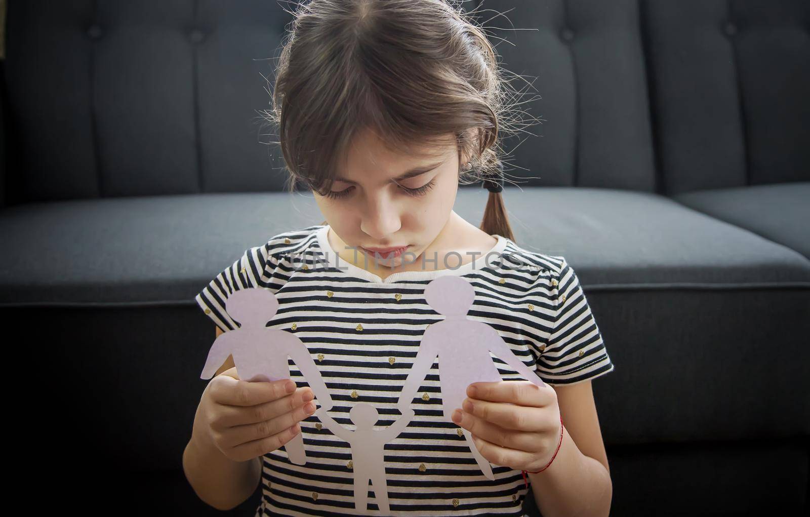 Child with a paper family in his hands. the concept of divorce, custody and child abuse. Selective focus. People.