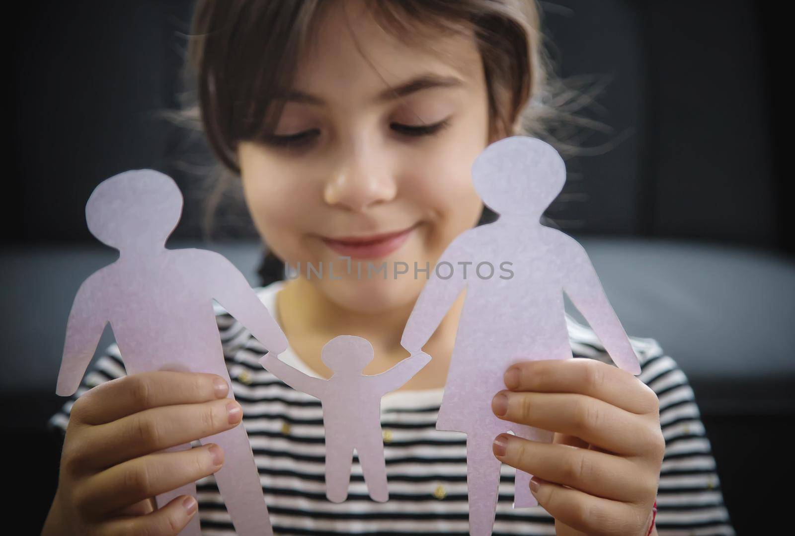 Child with a paper family in his hands. Selective focus. People.