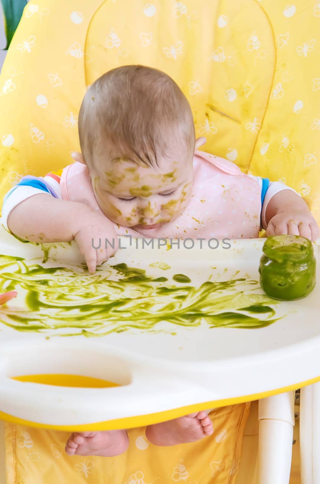 Little baby eats broccoli puree himself. Selective focus. People.