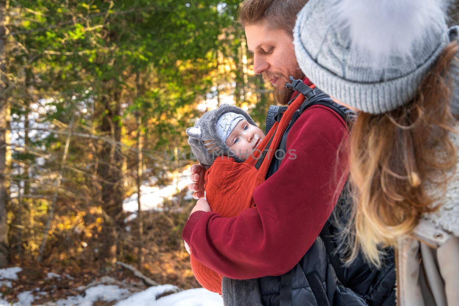 Babywearing winter walk of young parents with their children outdoor, copy space.