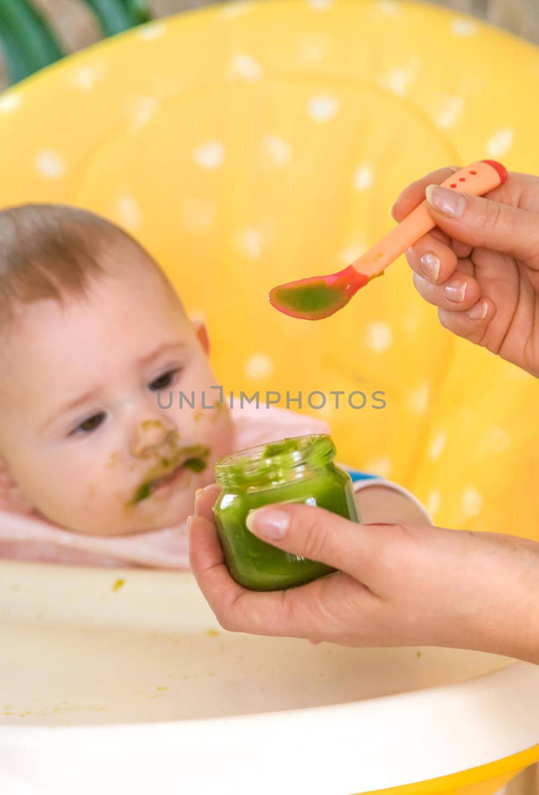 Little baby is eating broccoli vegetable puree. Selective focus. by yanadjana