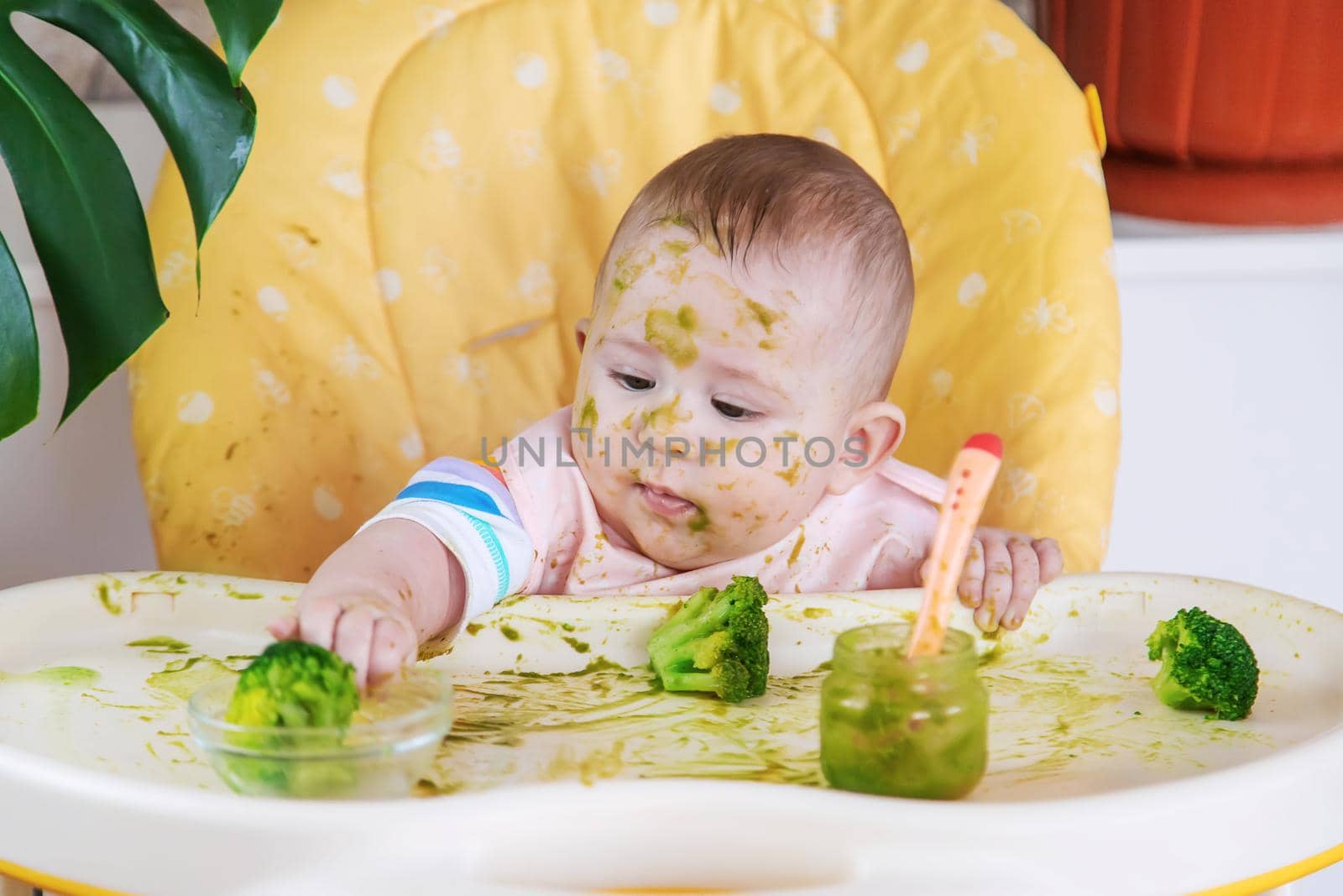 Little baby eats broccoli puree himself. Selective focus. by yanadjana