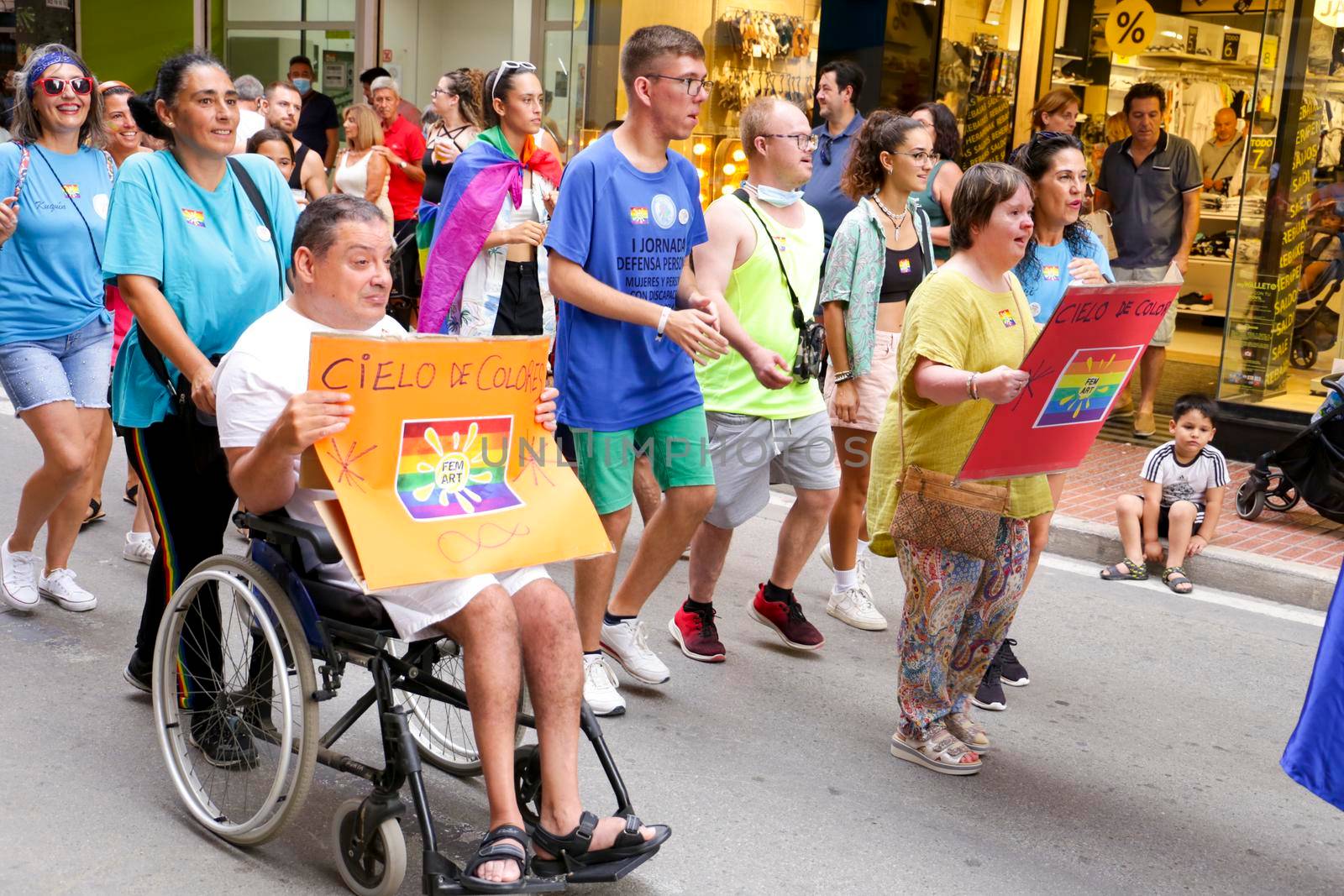 Santa Pola, Alicante, Spain- July 2, 2022: Spanish People with disabilities attending Gay Pride Parade with rainbow flags, banners and colorful costumes