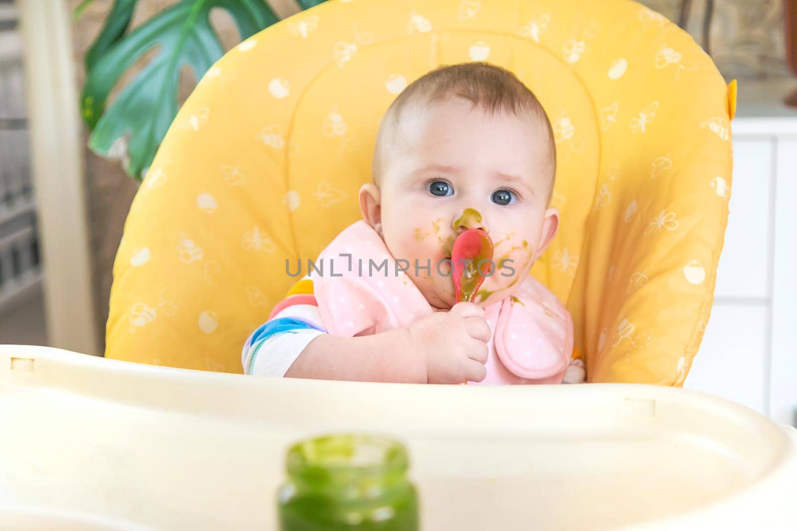 Little baby is eating broccoli vegetable puree. Selective focus. by yanadjana