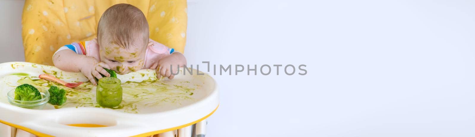 Little baby eats broccoli puree himself. Selective focus. People.