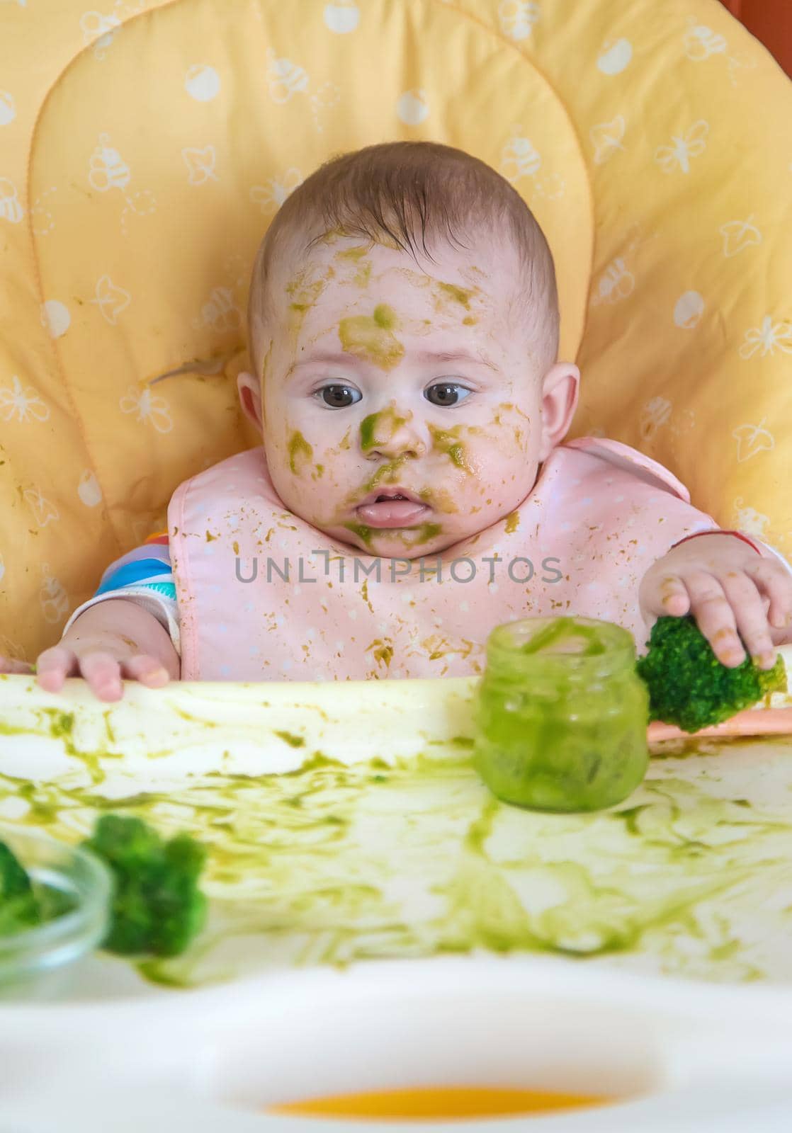 Little baby eats broccoli puree himself. Selective focus. by yanadjana