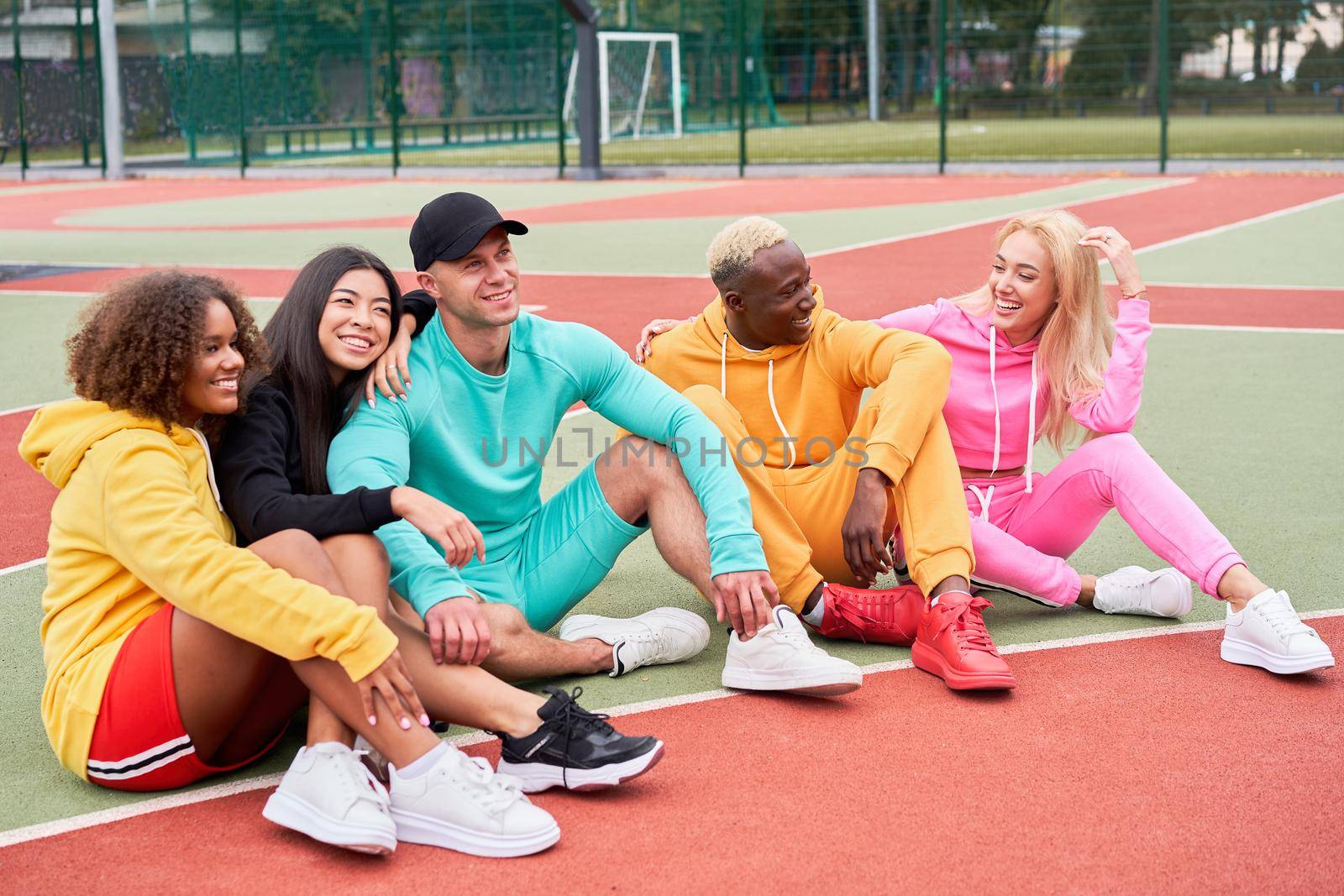 Multi-ethnic group teenage friends. African-american asian caucasian student spending time together Multiracial friendship Happy smiling People dressed colorful sportswear meeting outdoor sportground