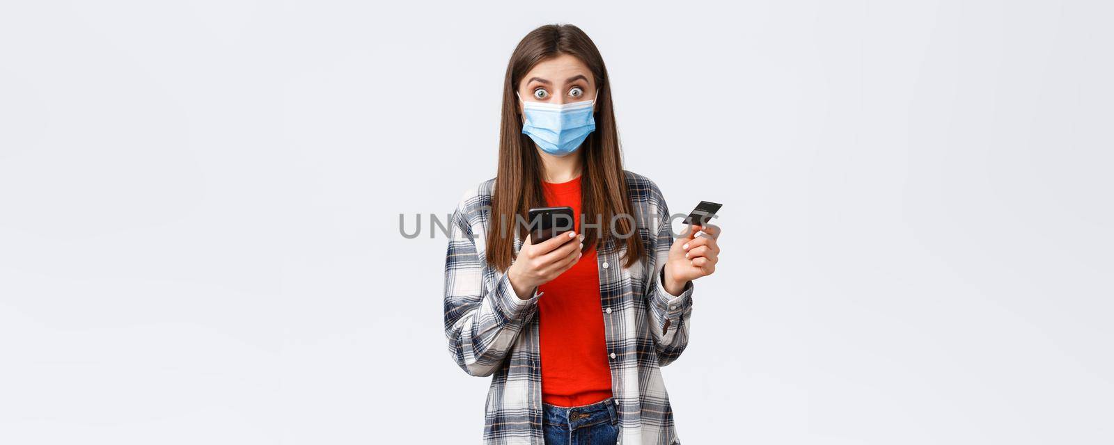 Coronavirus outbreak, working from home, online shopping and contactless payment concept. Surprised girl receive bonus discount for paying with credit card, holding mobile phone by Benzoix