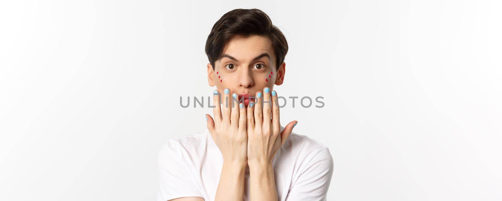 People, lgbtq and beauty concept. Beautiful gay man showing blue nail polish on fingernails and looking at camera, have manicure, standing over white background.