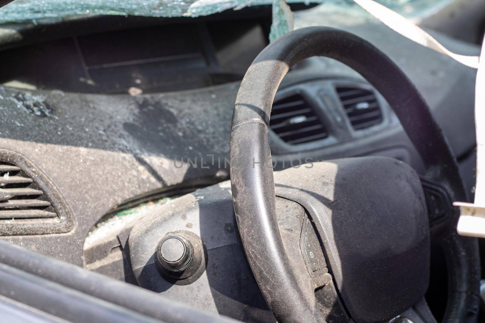 Close-up of the steering wheel of a car after an accident. The driver's airbags did not deploy. Soft focus. Broken windshield with steering wheel. Vehicle interior. Black dashboard and steering wheel