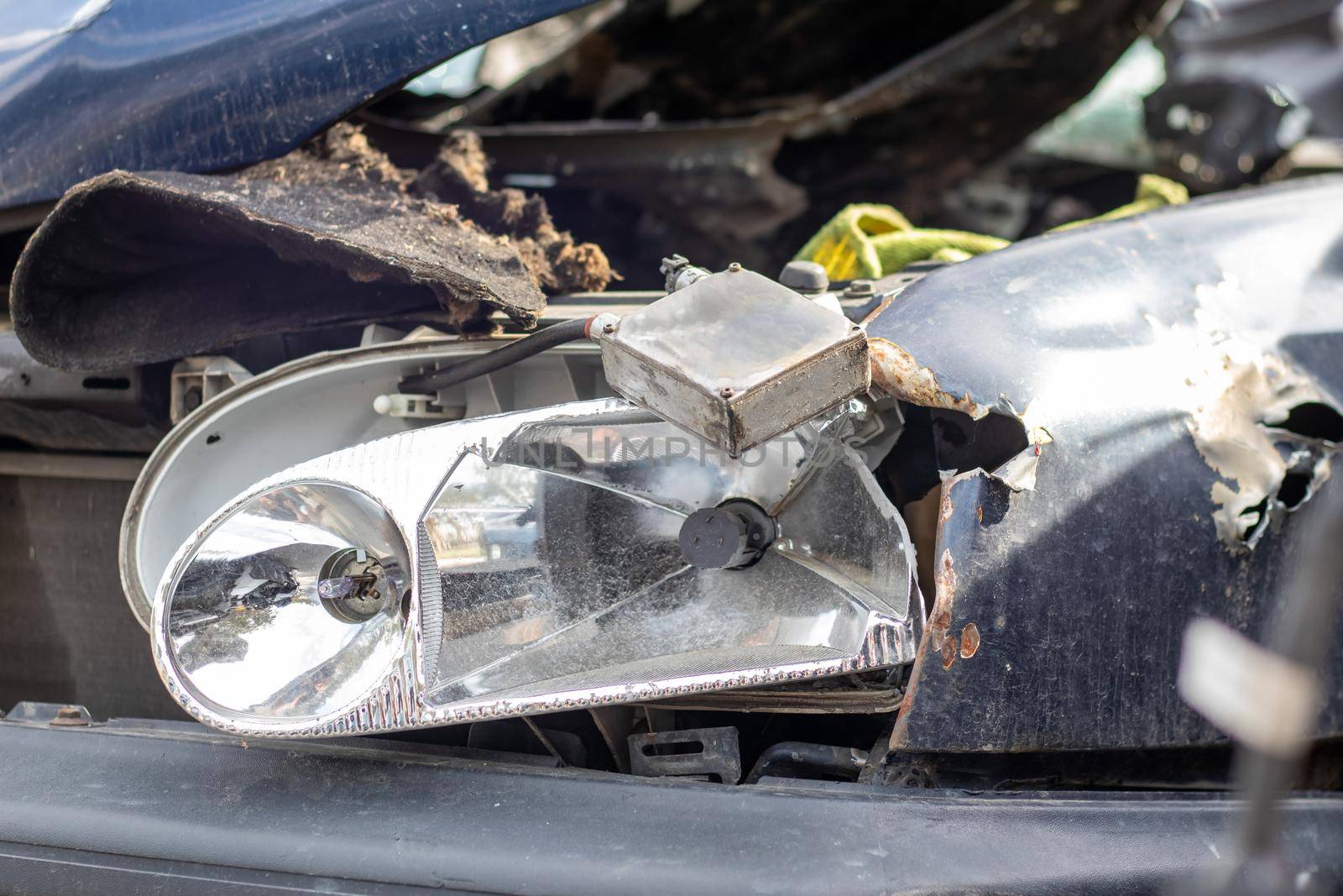 Broken headlights as a result of a collision. Broken blue car after an accident. Car accident concept. Damaged emergency headlight, hood and bumper. Damage to the body of the car after the accident